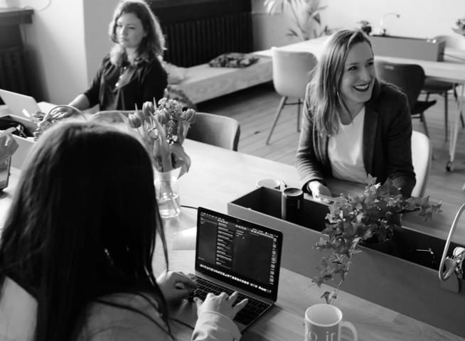 Three women working on their laptops at a table.